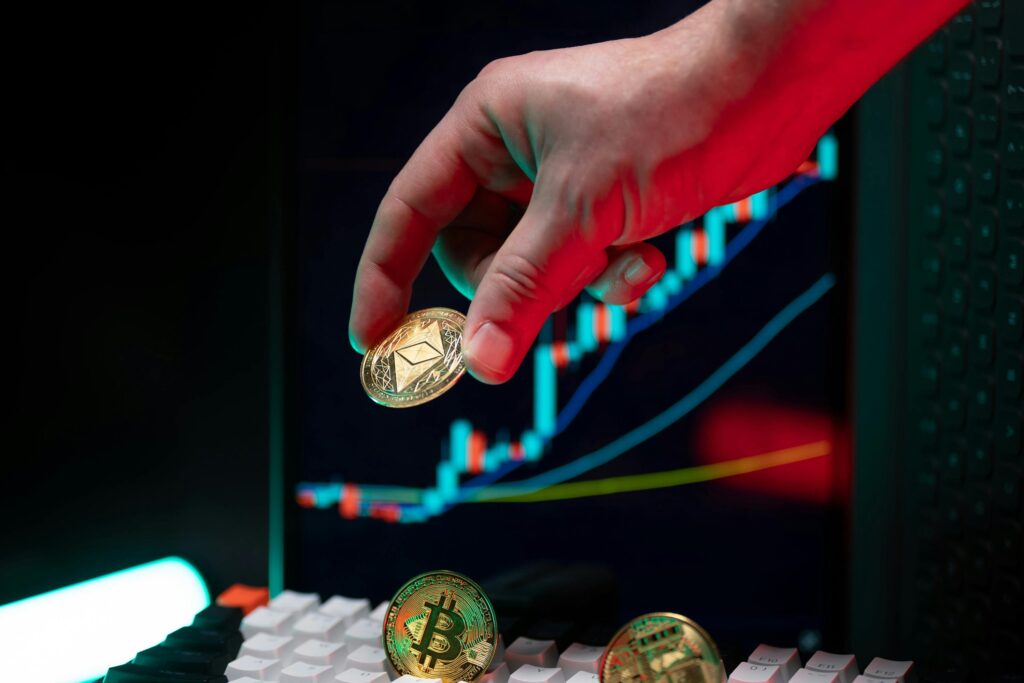 A hand holding cryptocurrency coins with a financial chart in the background, depicting market trends.